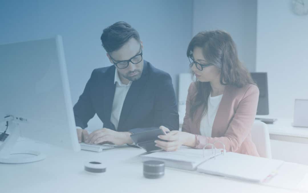 Two professionals reviewing documents at a desk, blue-tinted photo