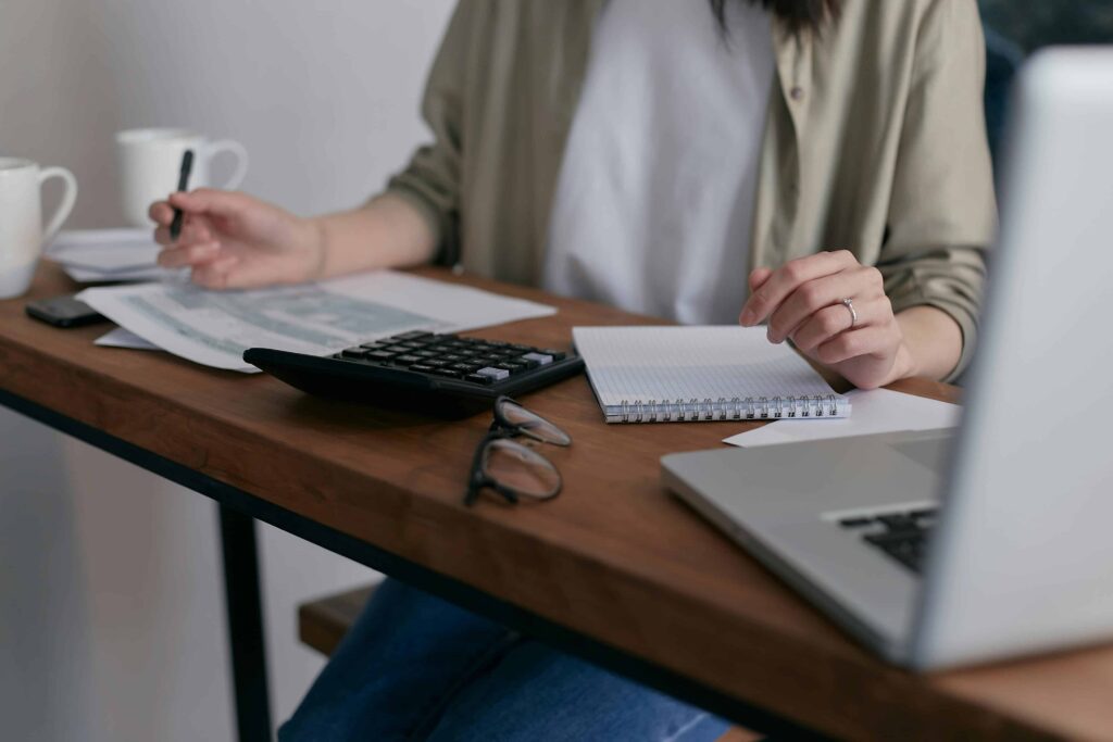 A woman sits at a desk with a laptop and a coffee cup, focused on addressing DME billing errors affecting revenue.