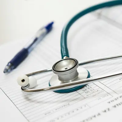 A turquoise stethoscope and a blue pen resting on top of a medical document or form
